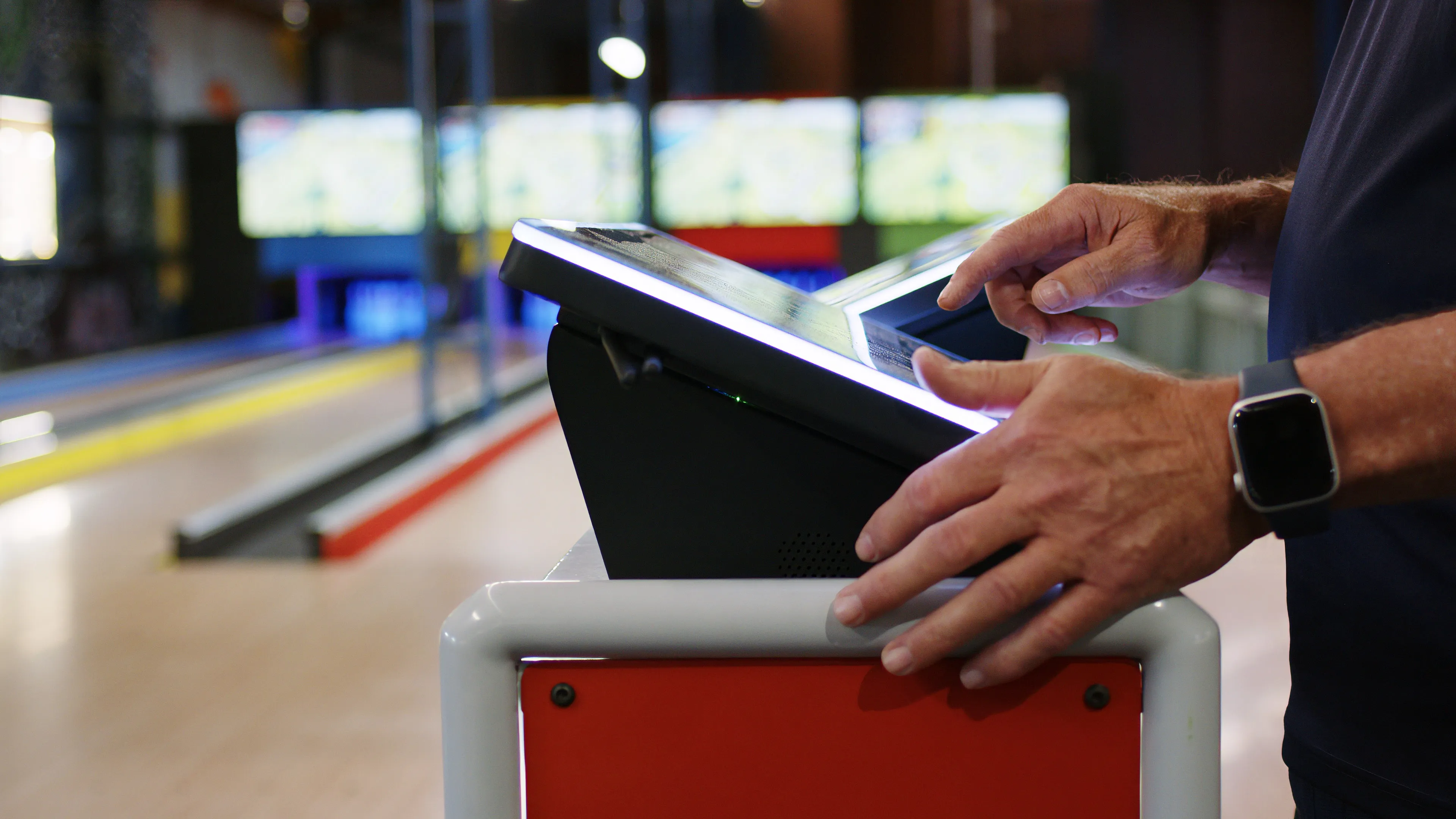 Hands operating the LaneCraft touchscreen console mid-game, with lane screens behind
