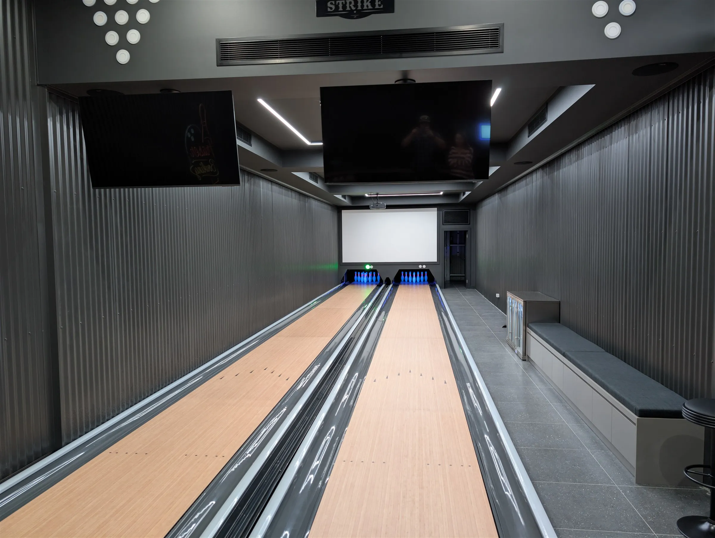 Finished two-lane private bowling installation with tiled surrounds, bench seating and lit pin decks