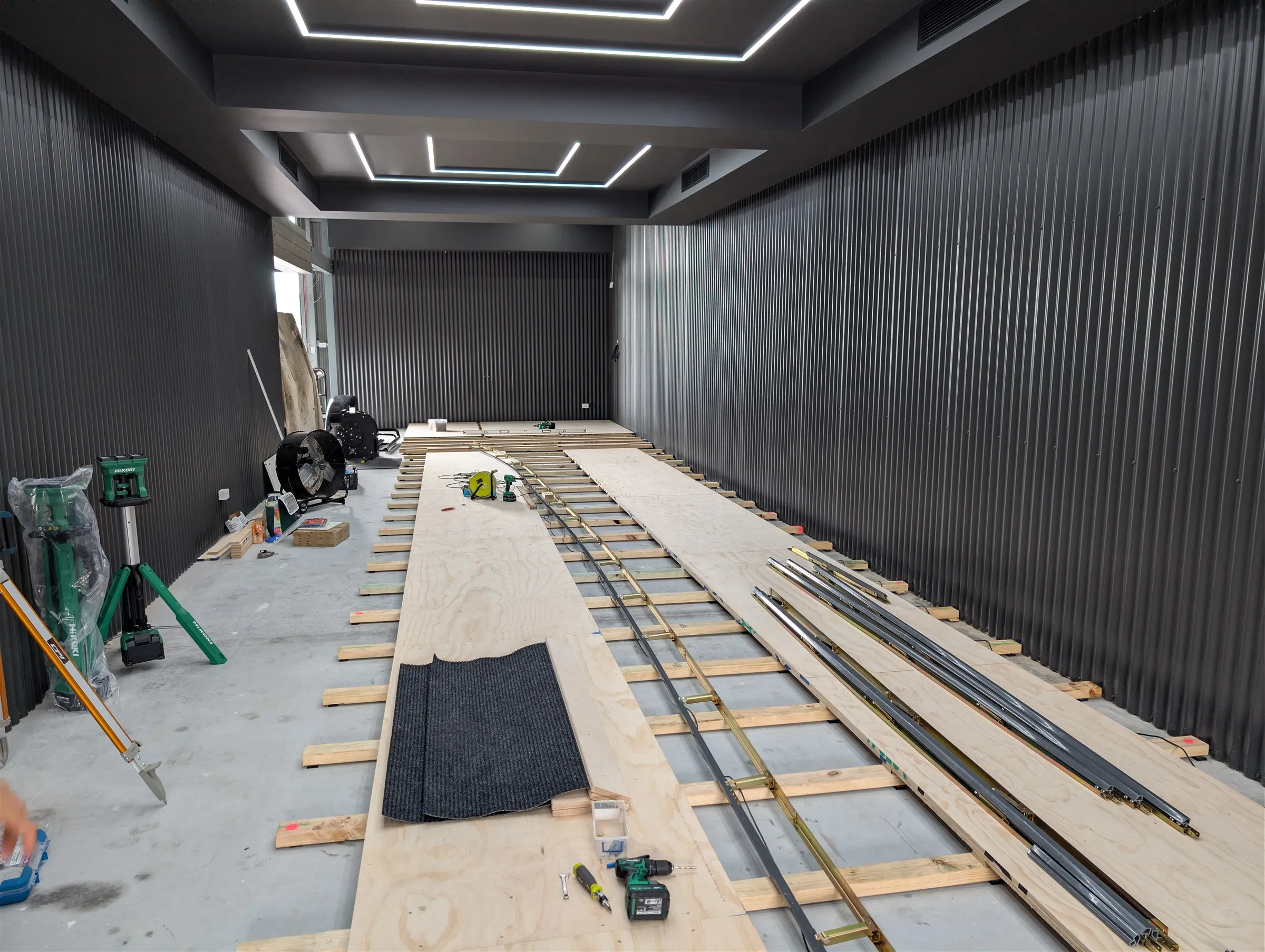 Bowling lane substructure being laid out on the existing concrete slab, with timber bearers, plywood decking and steel rails
